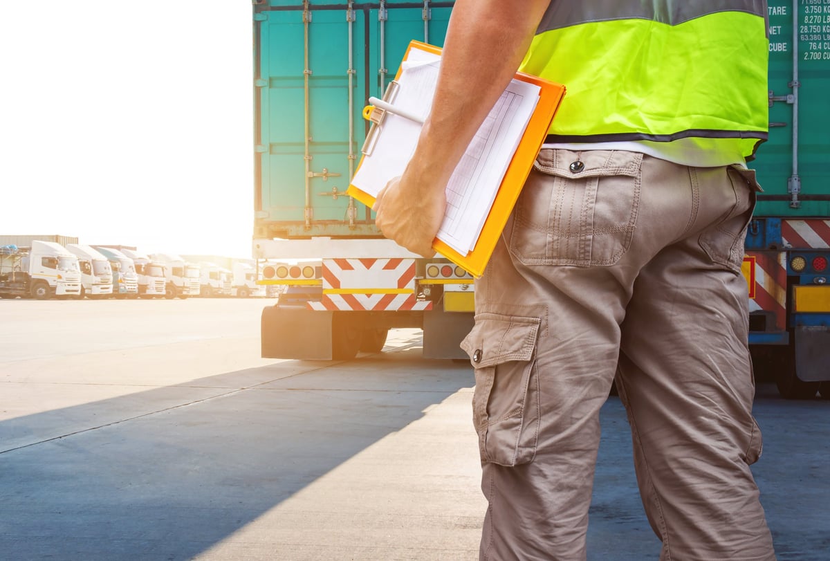 Truck drivers holding a clipboard while checking a semi-trailer